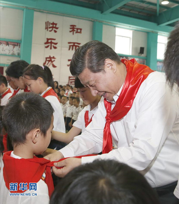 2014年5月30日,在北京市海淀區(qū)民族小學(xué)的少先隊入隊儀式上,習(xí)近平為新少先隊員系上紅領(lǐng)巾。新華社記者鞠鵬攝